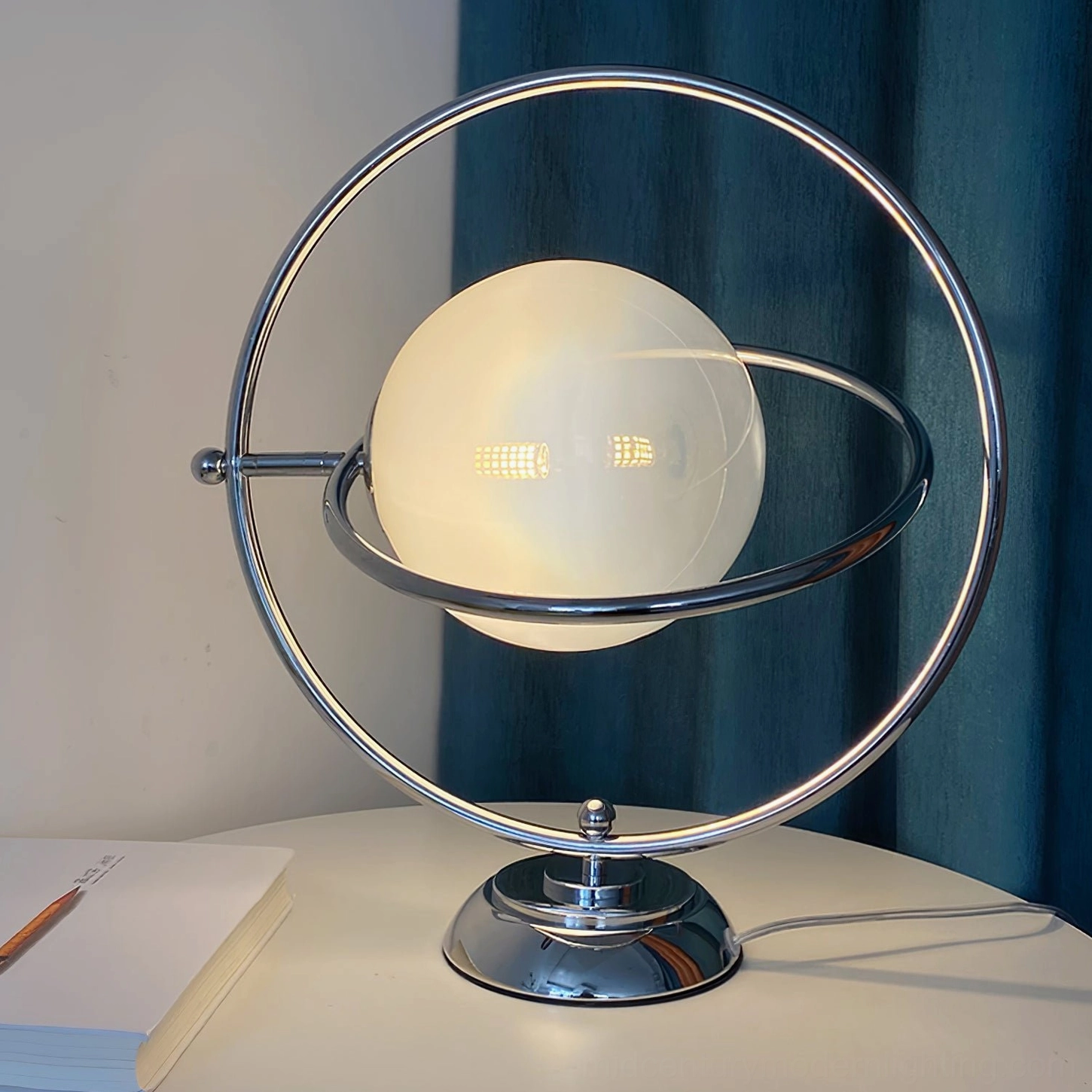 Space age rotating planet lamp on modern desk with 360-degree orbital ring and warm LED glow