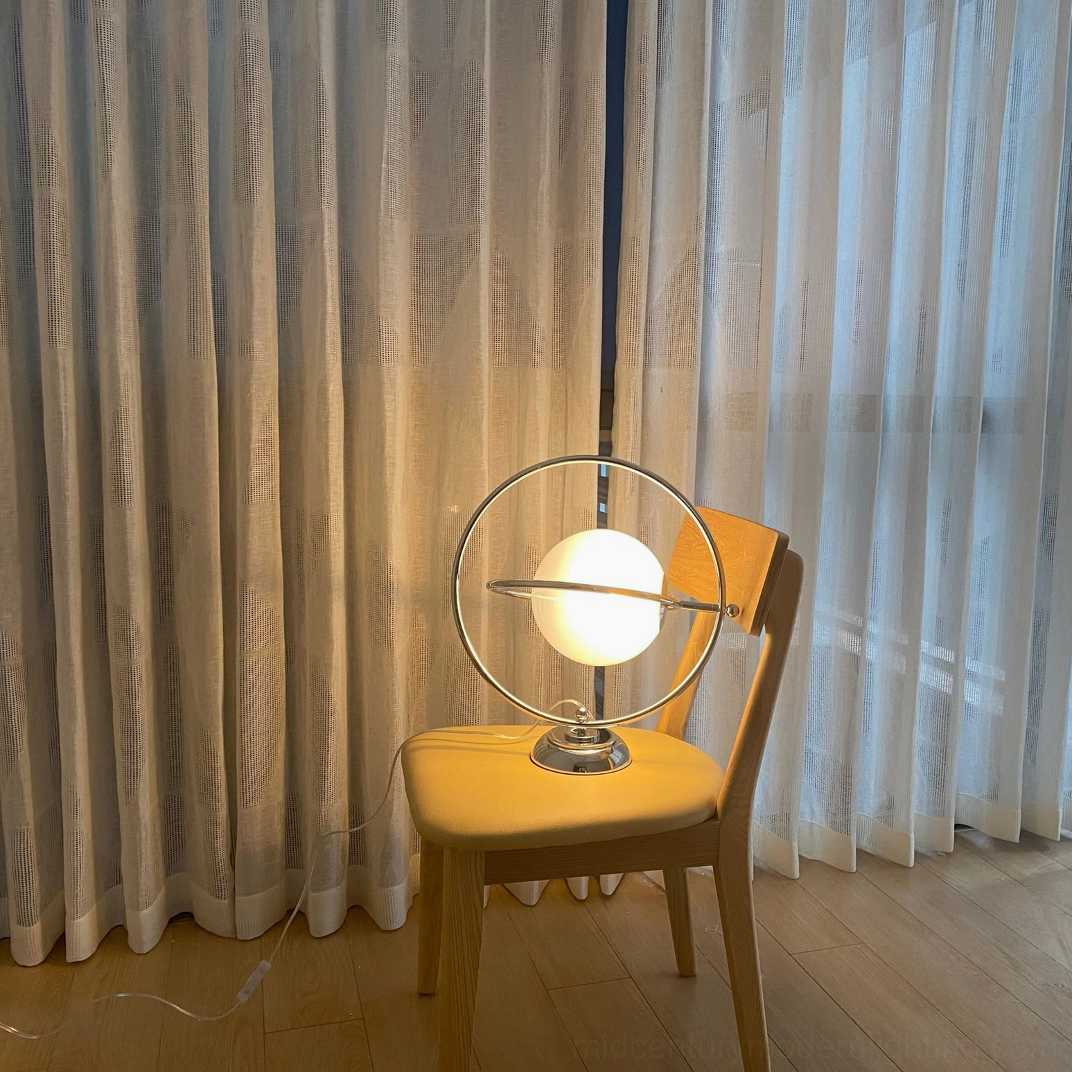 Rotating planet lamp beside chair in living room with warm wood-tone home decor aesthetic