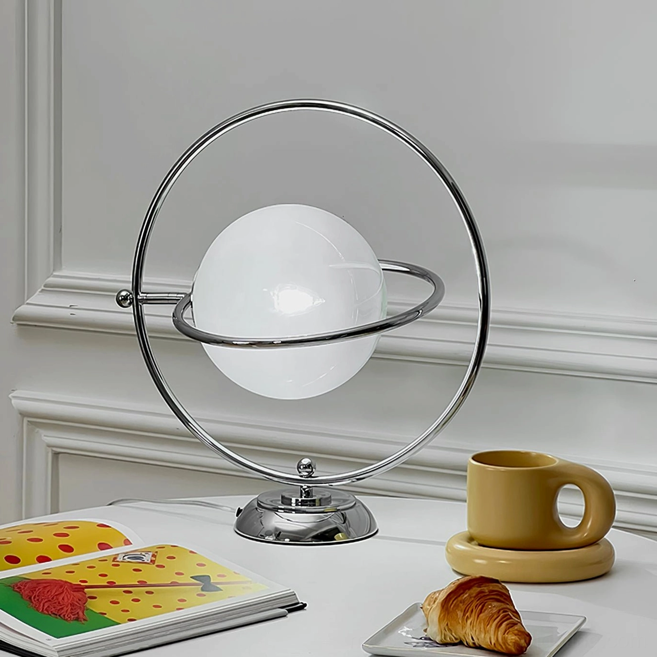 Polished silver planet table lamp with sculptural metal frame and white glass shade