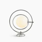 Rotating Planet table lamp with polished silver metal frame and frosted white glass globe on white studio background