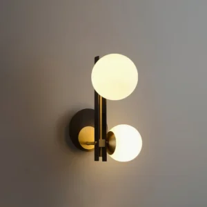 Close-up detail of Planeta wall sconce showing warm LED illumination through frosted glass, matte black backplate with brass accents