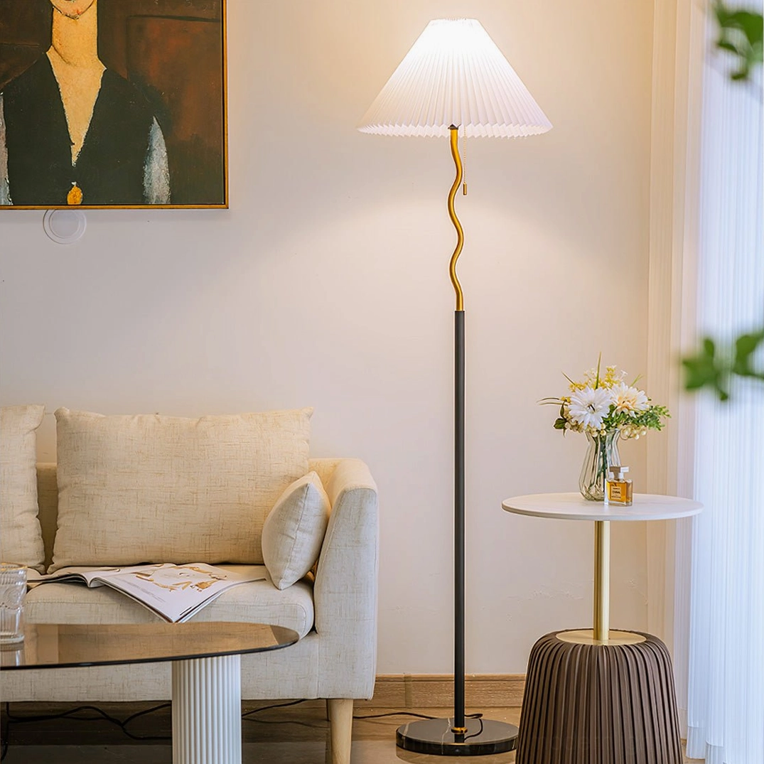 Modern pleated floor lamp in contemporary living room with sofa, three-quarter angle showing warm ambient lighting