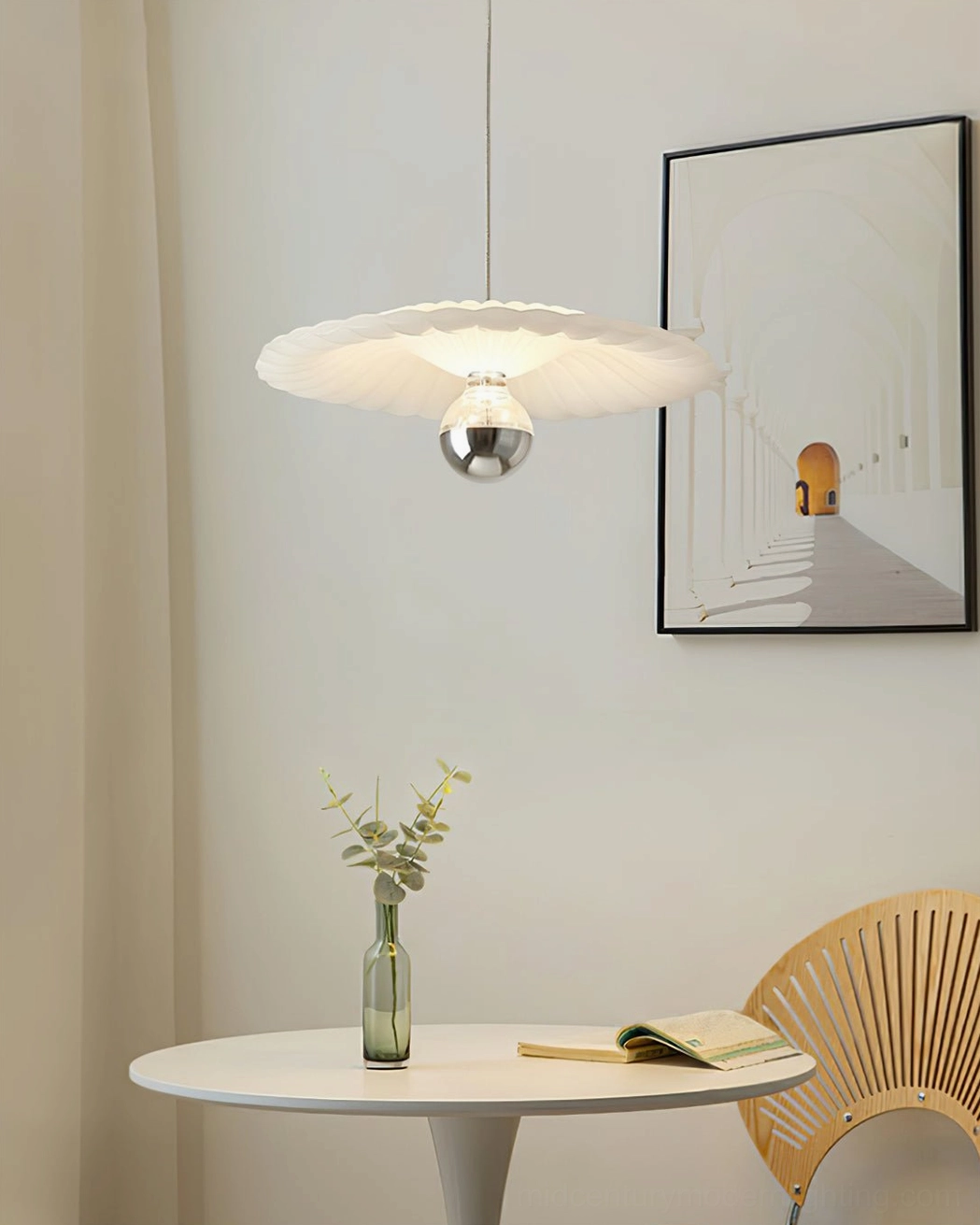 Pleated pendant light above dining table in minimalist modern space with round furniture