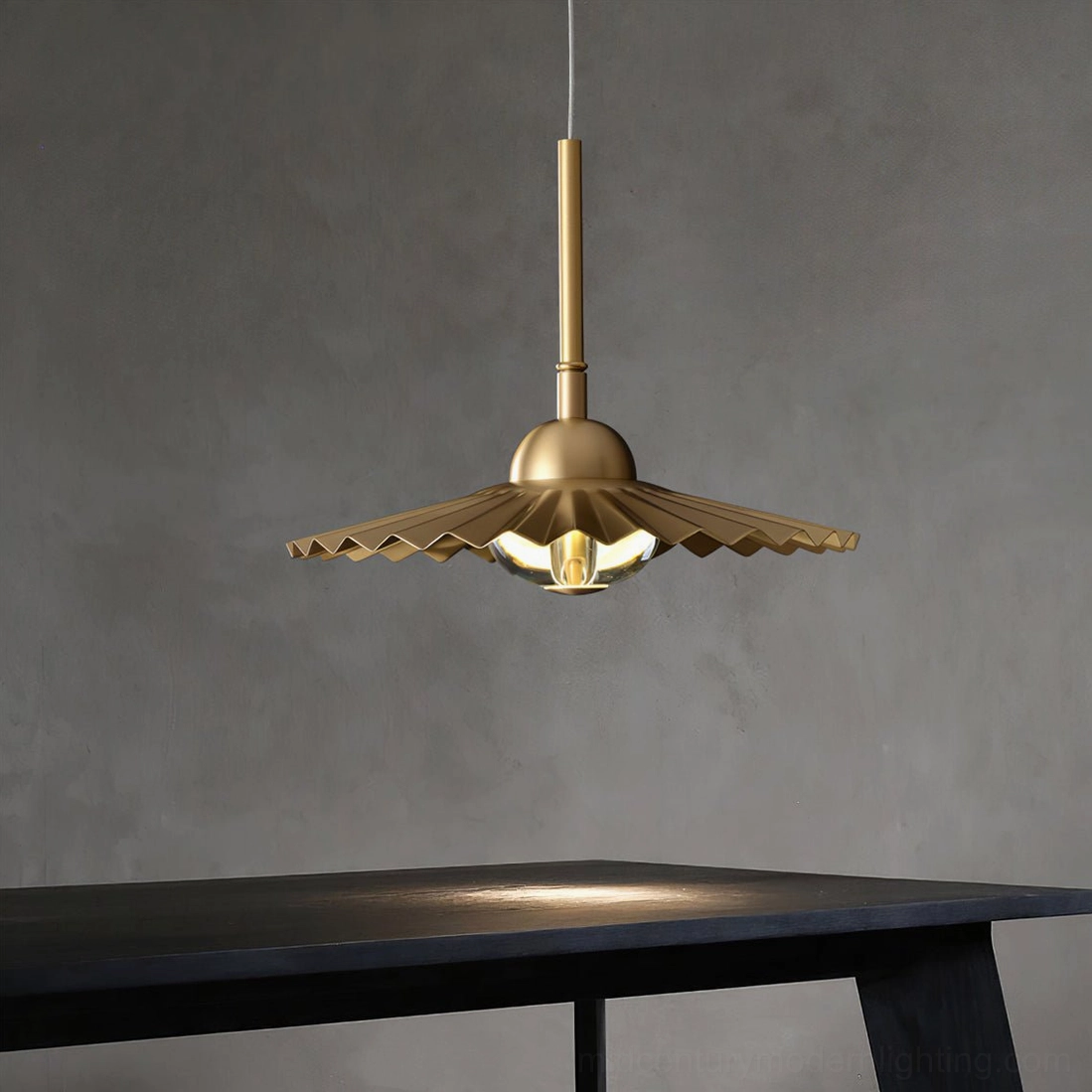 Single plié pendant light with matte brass finish and accordion pleats suspended in minimalist dark dining corner interior