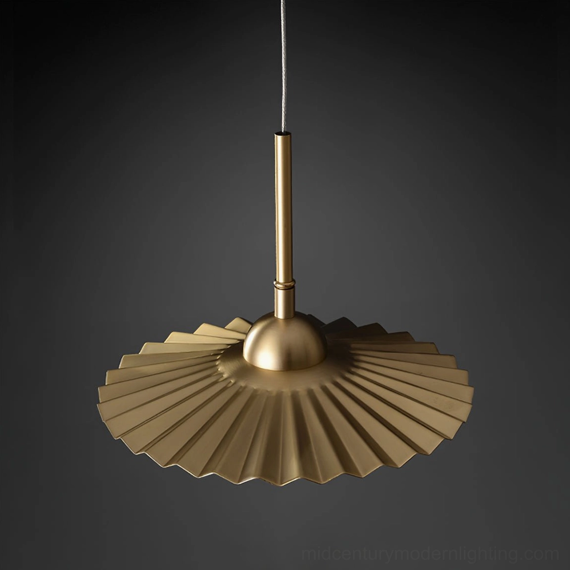 Plié brass pendant suspended above dining surface demonstrating scale and proportion for interior spaces