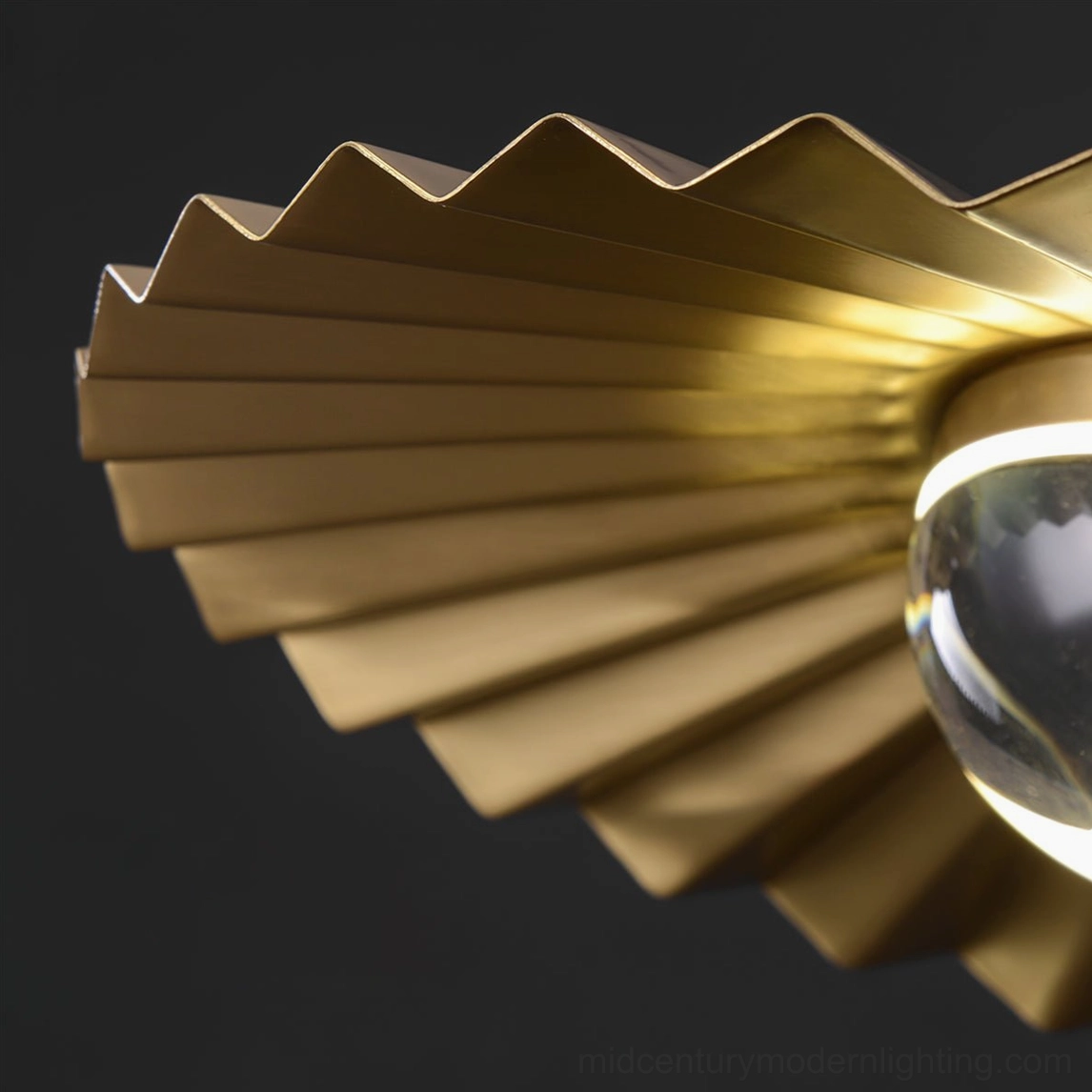 Macro view of plié pendant shade revealing corrugated pleated brass texture and light diffusion channels
