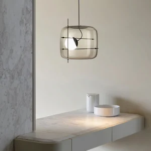 Smoked grey glass pendant light with black suspension cord, side eye-level view in minimalist vanity space