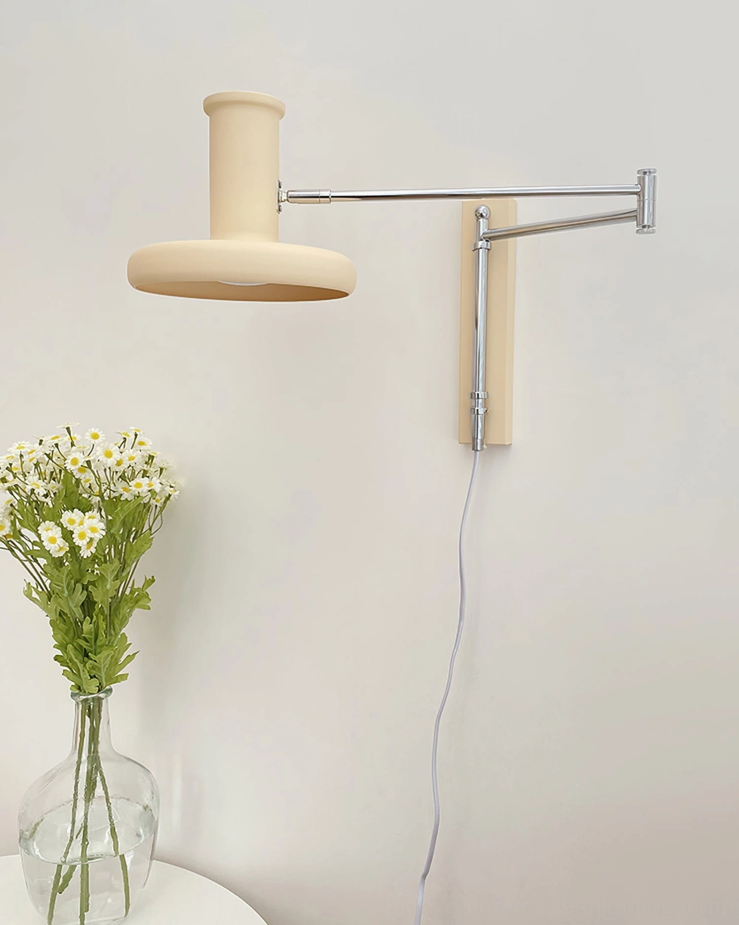 Cream and chrome plug-in wall sconce demonstrating elegant minimalist design and functional swing arm positioning capability
