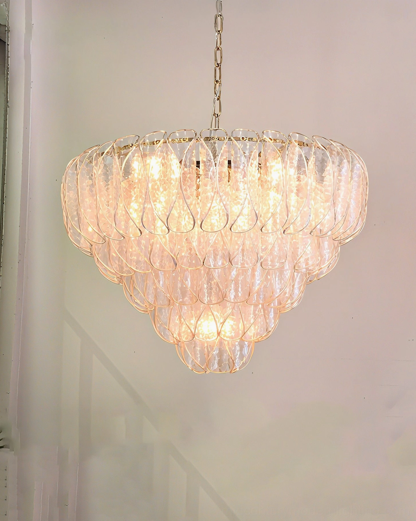 Poliedri tiered glass chandelier side view in residential staircase with soft warm glow and sculptural detail