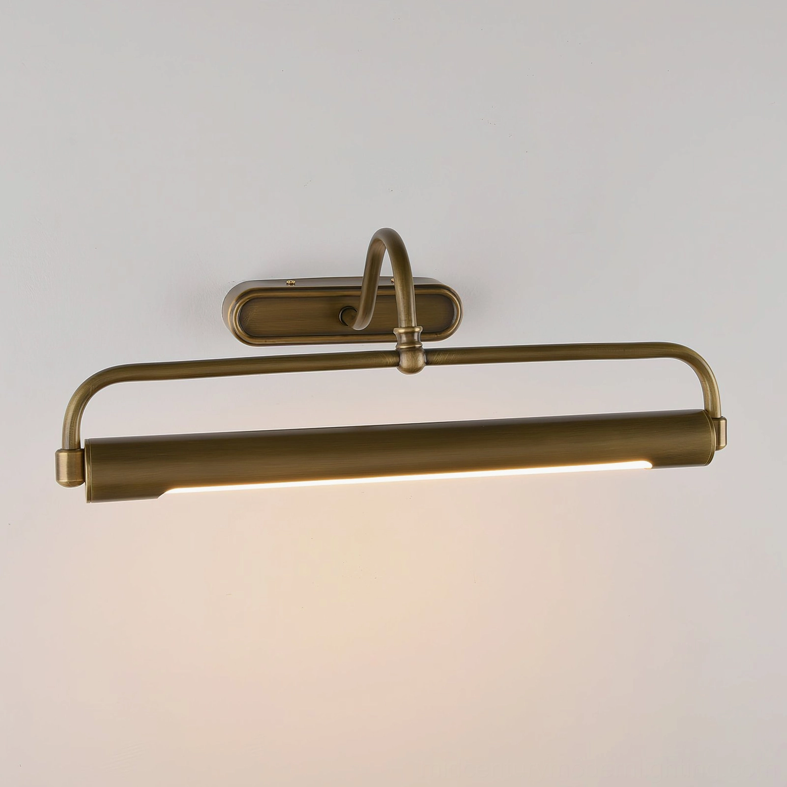 Polished brass gooseneck sconce mounted on light wall, warm integrated LED light source