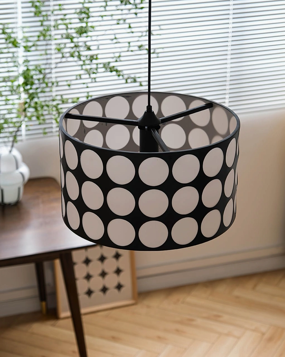 Polka dot pendant lamp suspended above dining area with exposed light structure and window blinds