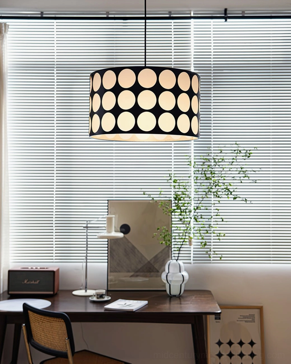 Illuminated black and white polka dot pendant lamp glowing warm light through fabric shade in office space