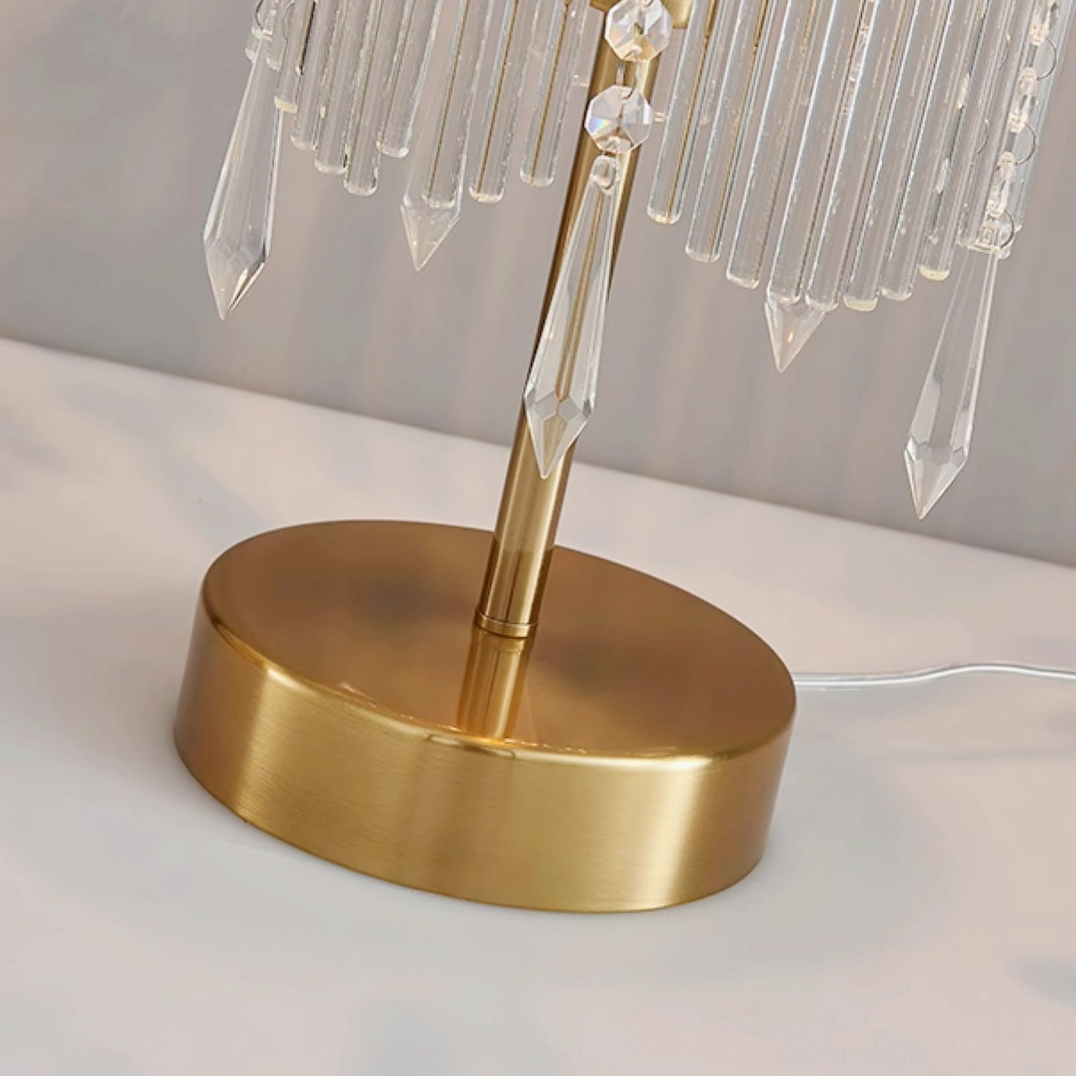 Close-up of Popity lamp base assembly with brushed brass finish and suspended crystal pendants detail