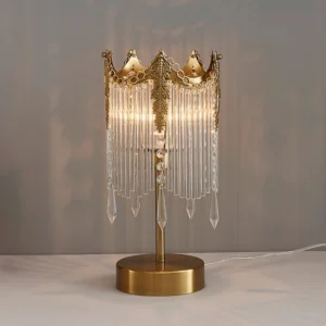 Illuminated Popity table lamp showing warm light refraction through crystal strands and polished brass accents