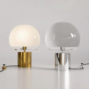 Pair of Porcino mid-century modern table lamps in silver and gold finishes with different glass shades on minimalist white tabletop