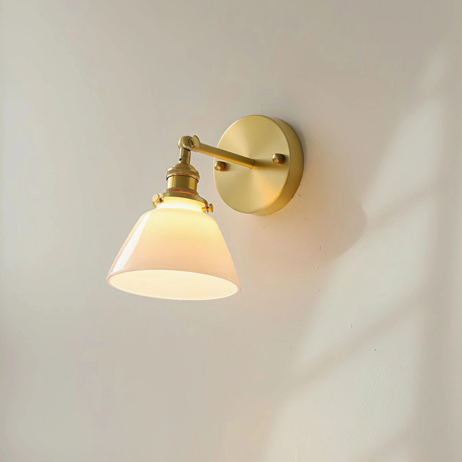 Compact Portland model A wall sconce illuminated, showing scale with frosted conical shade and brass base