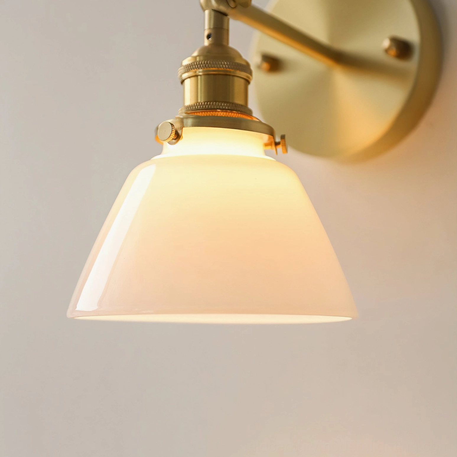 Close-up detail of Portland wall sconce fixture showing brass components and frosted conical shade illuminated