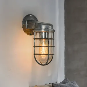 Distressed silver maritime wall lamp mounted on residential gray wall showing aged industrial finish detail