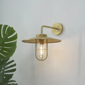 Portree brass nautical wall lighting mounted on interior wall with monstera plant decoration