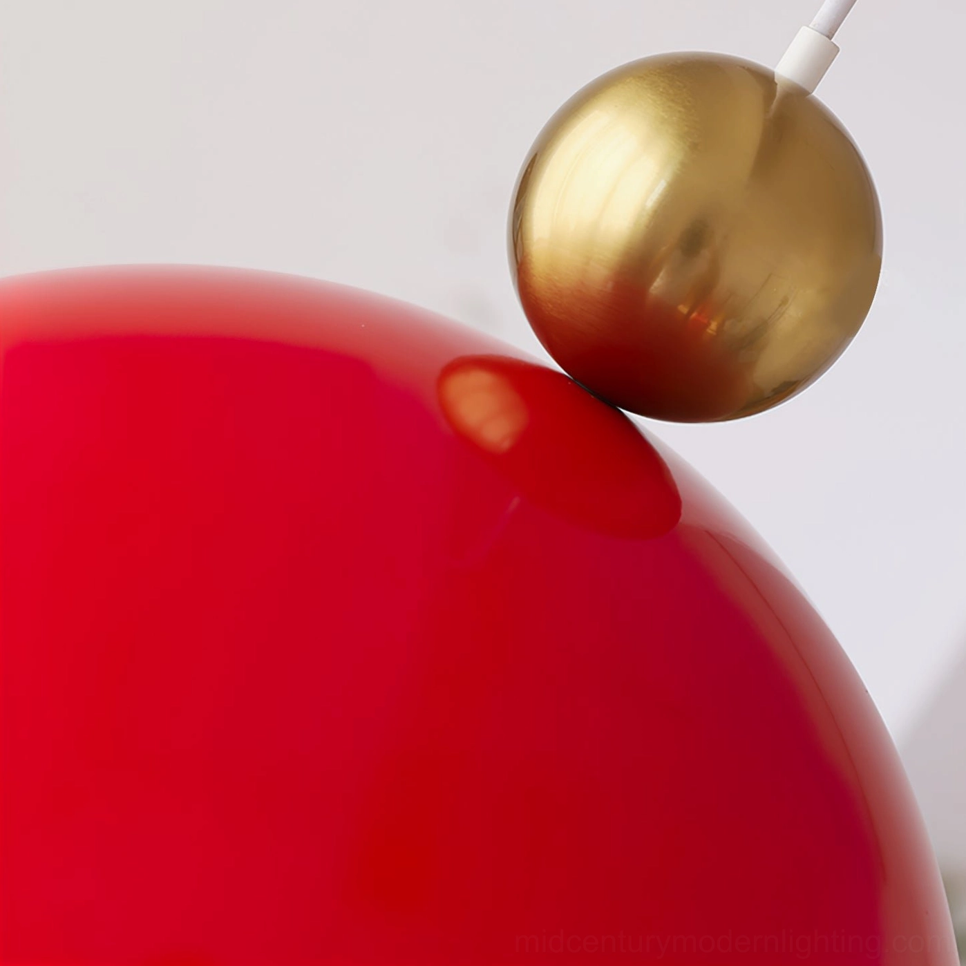 Close-up detail of red glossy dome pendant lamp fixture with brass metal sphere