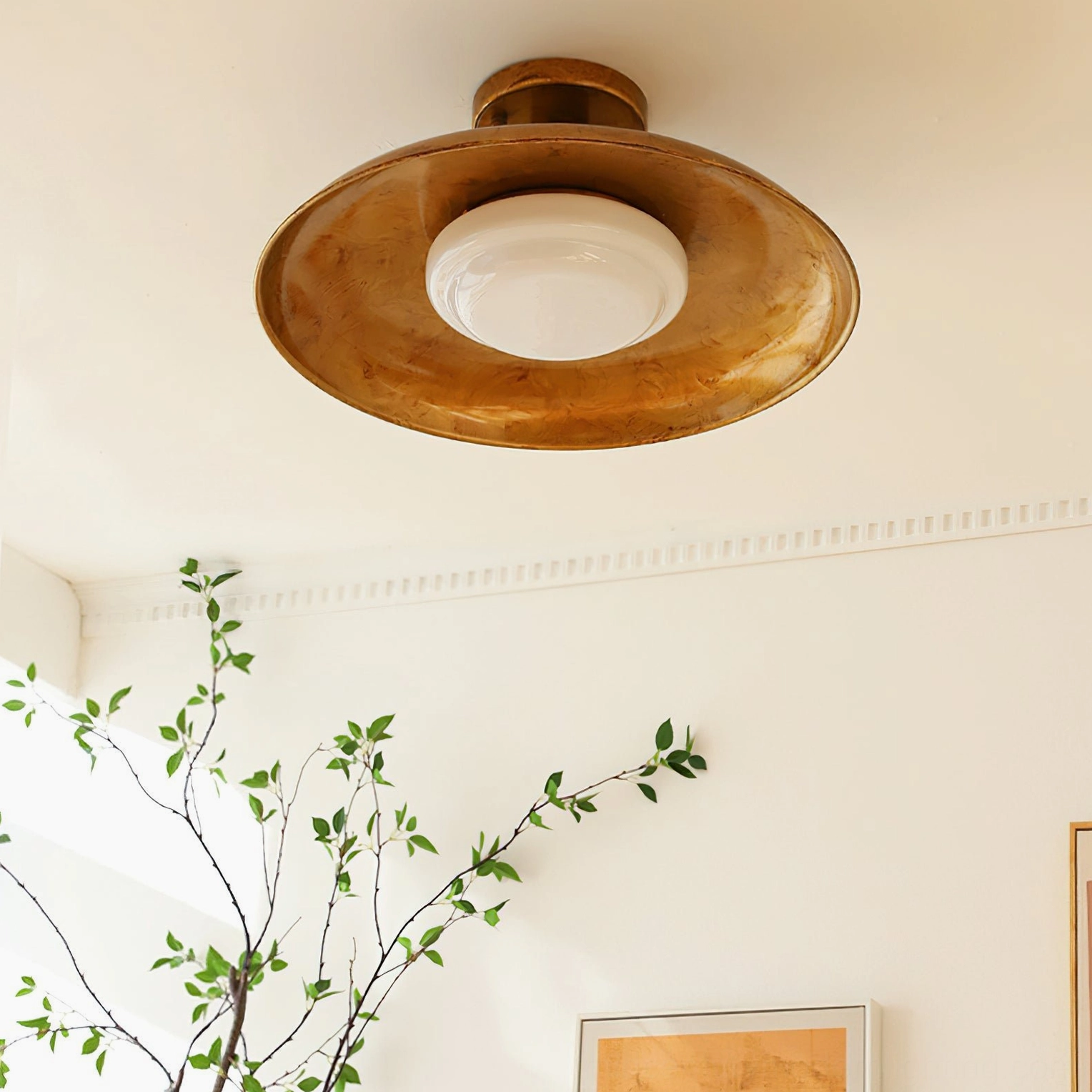 Ceiling-mounted industrial pot-lid light fixture in room setting with green plant and wall art decor
