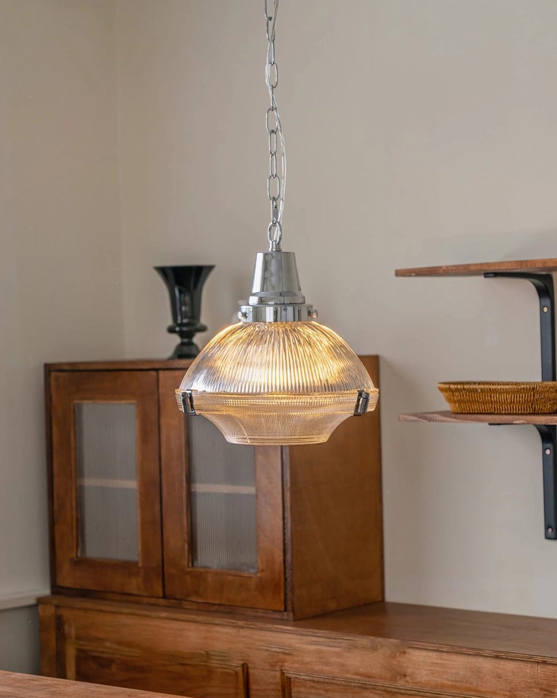 Amber-tinted ribbed glass pendant light with chrome hardware in vintage kitchen with open shelves