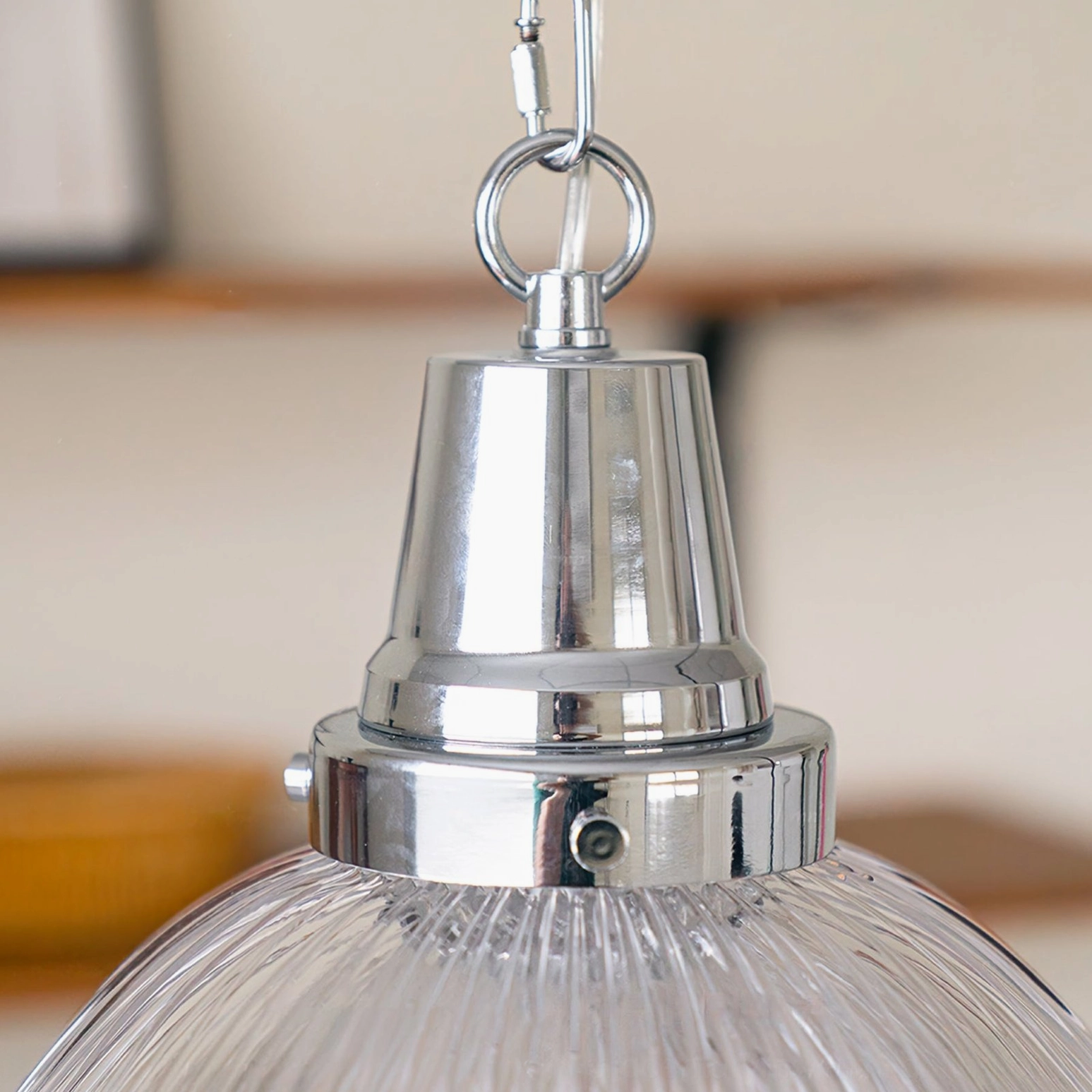Close-up detail of prismatic pendant light chrome metal hardware and ribbed glass base