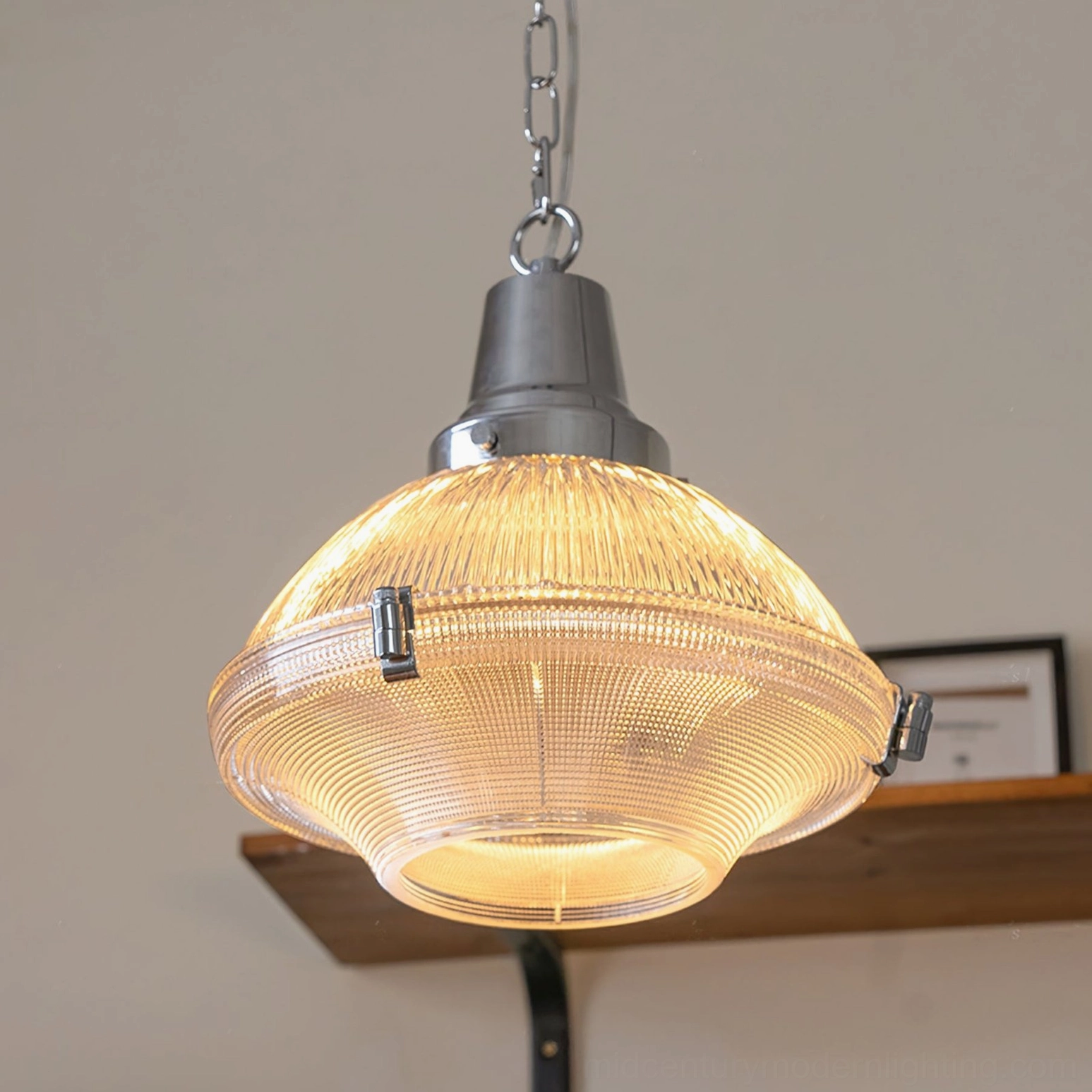 Warm glowing amber ribbed glass pendant light with chrome fixture on wall shelf