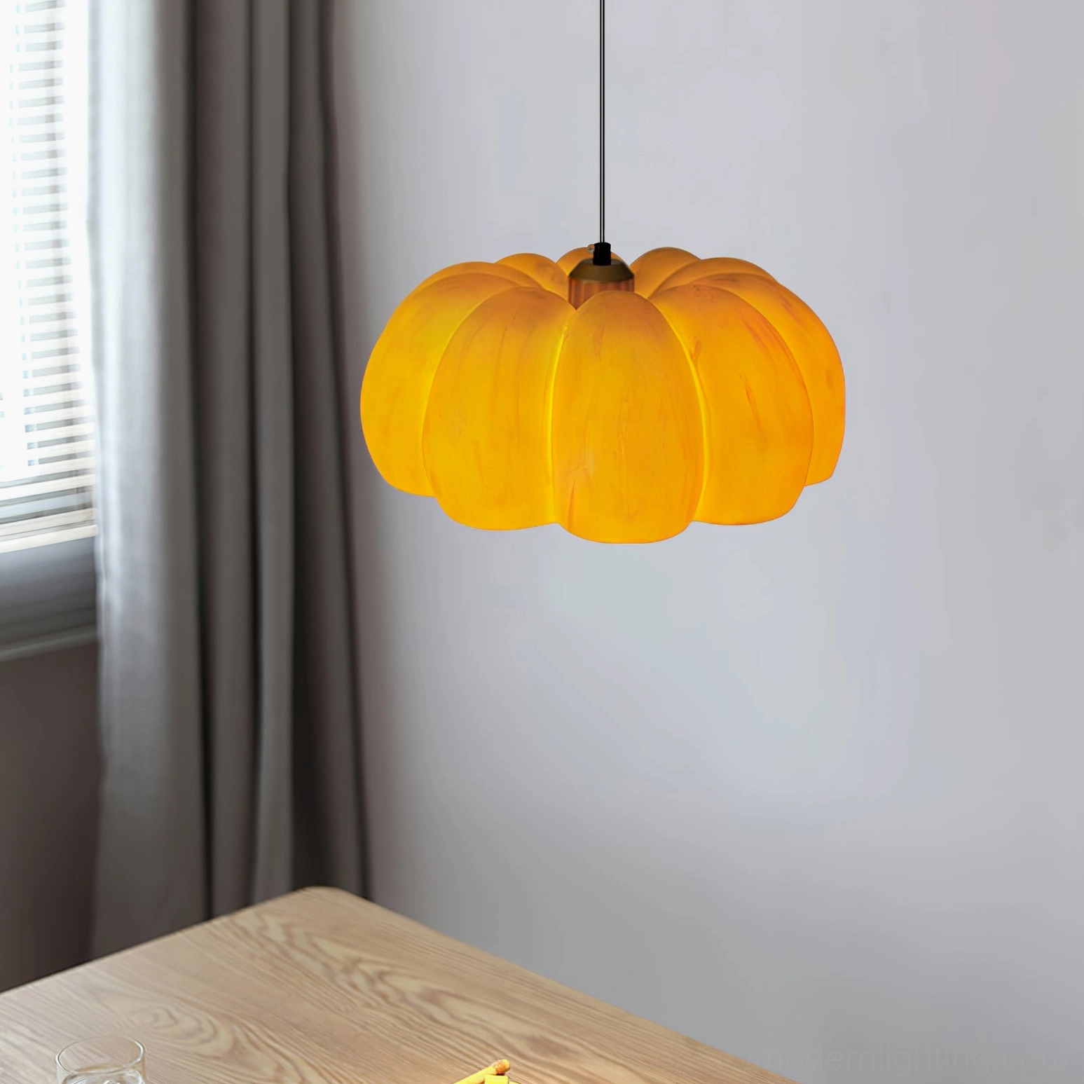 Low-angle view of ribbed pumpkin pendant lamp with warm amber shade above dining table corner