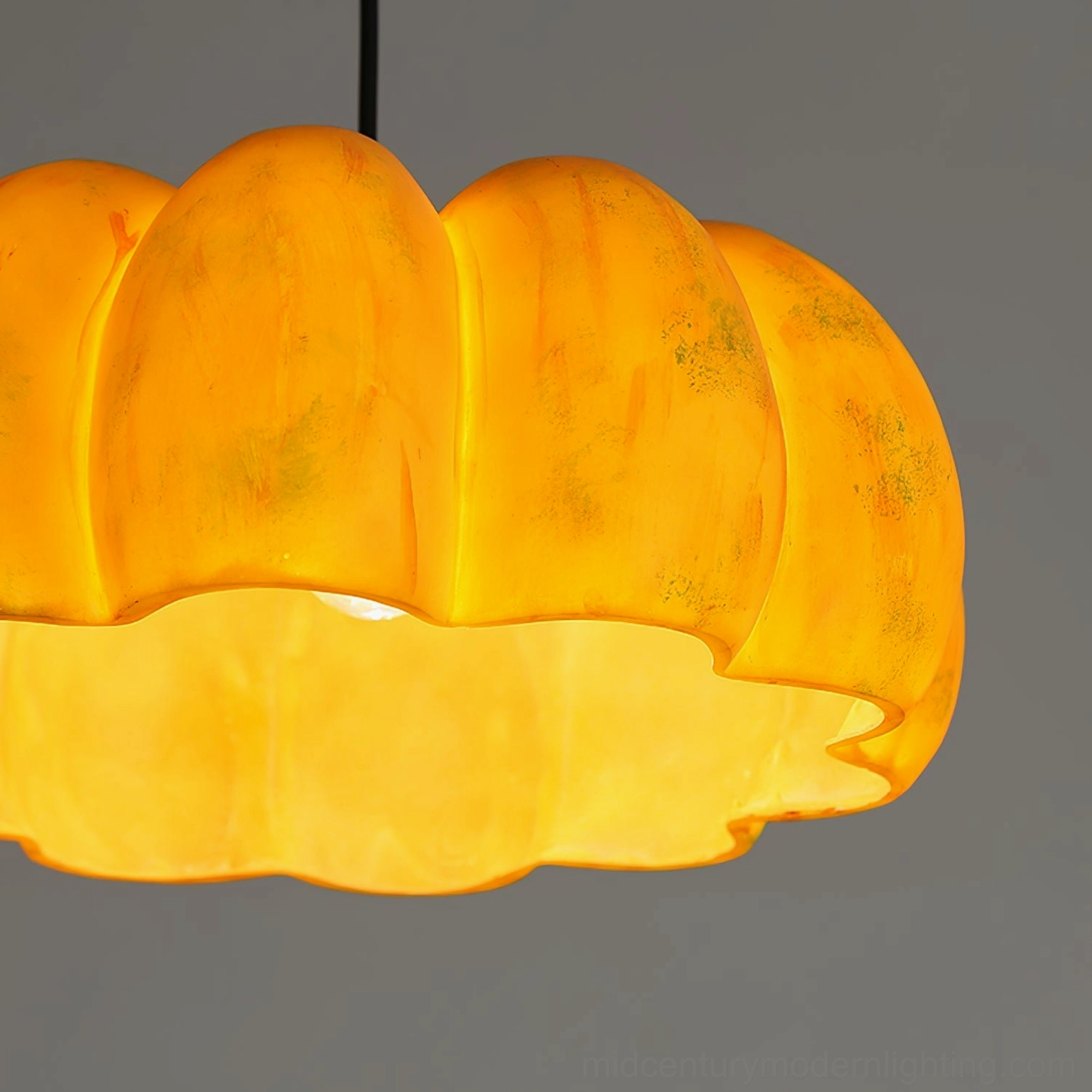 Large pumpkin pendant lamp as statement lighting fixture in modern dining room setting