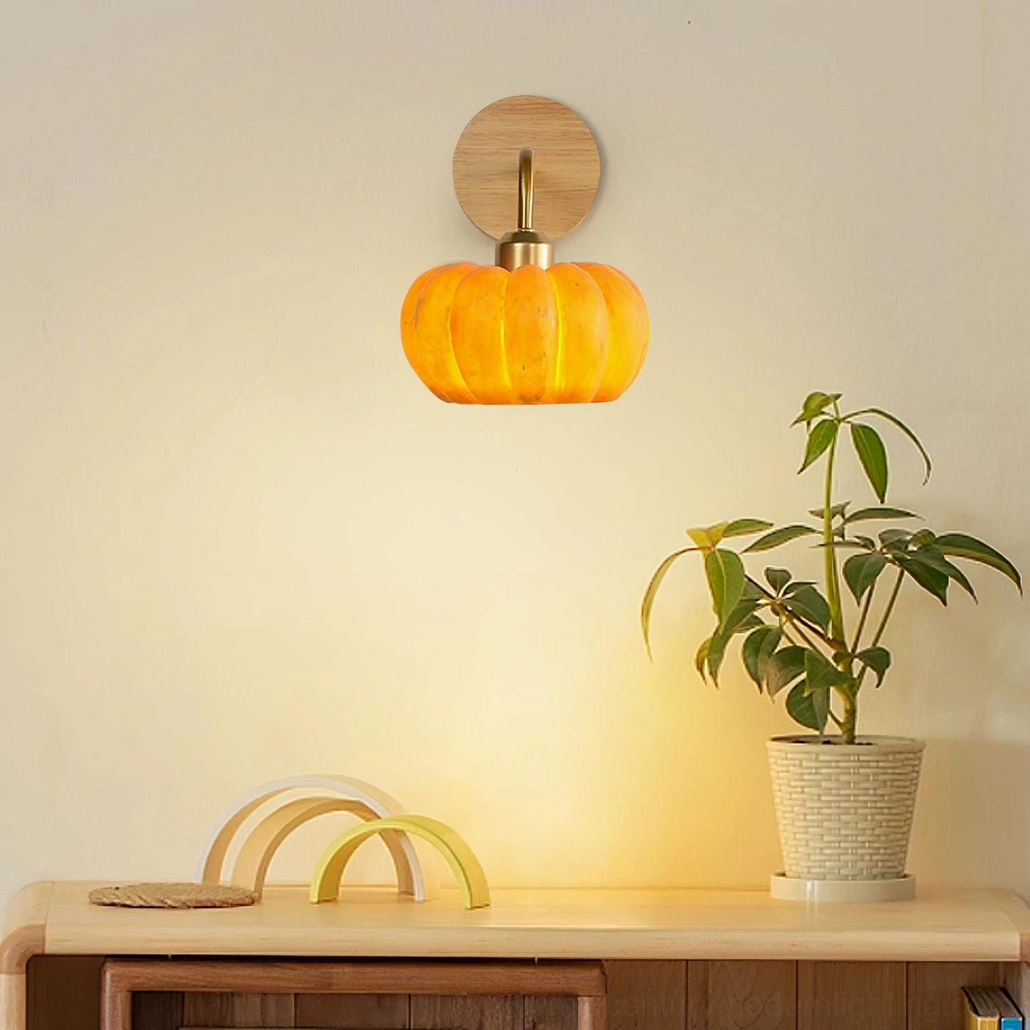 Pumpkin wall sconce on console table with potted green plant, low-angle view demonstrating sculptural design