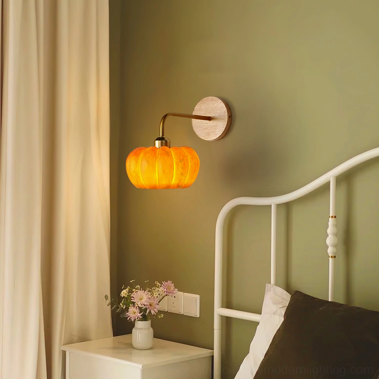 Pumpkin wall lamp in green bedroom with white metal bed frame, warm glow creating cozy bedside ambiance