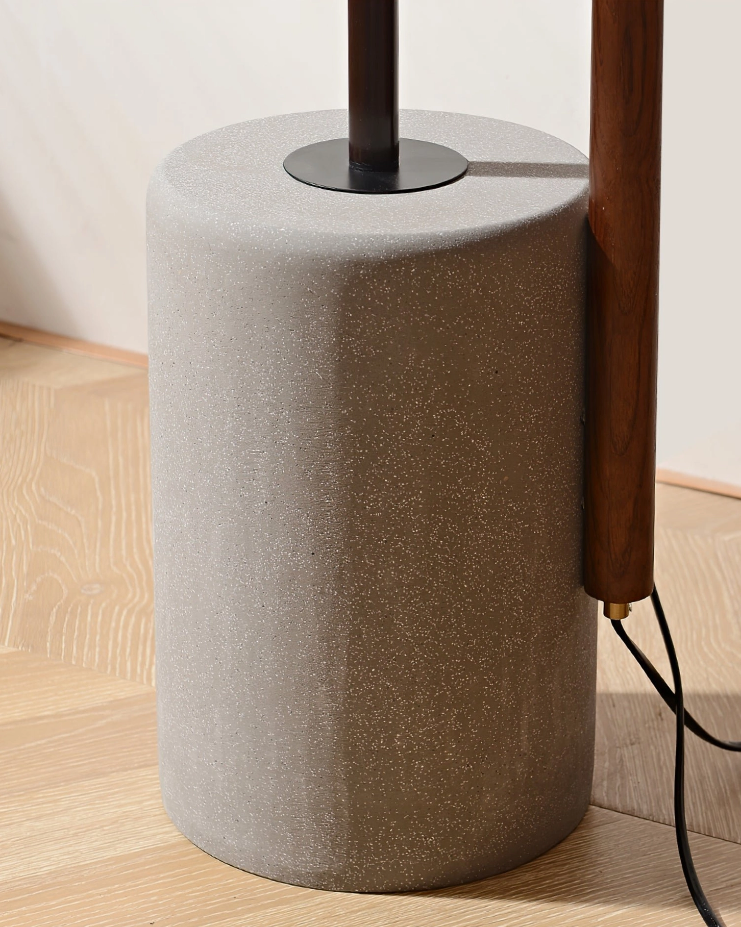 Close-up detail of Puro floor lamp concrete base, metal joint, and solid walnut wood pole