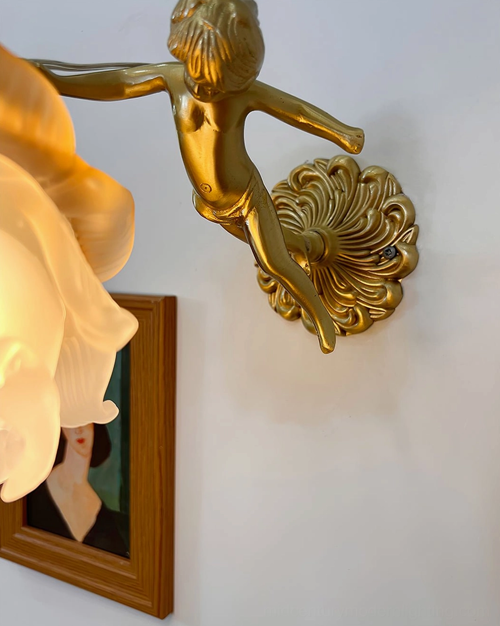Putti cherub brass wall sconce architectural detail shot showing intricate brass shell backplate and modeled angel figure with frosted glass flower shade