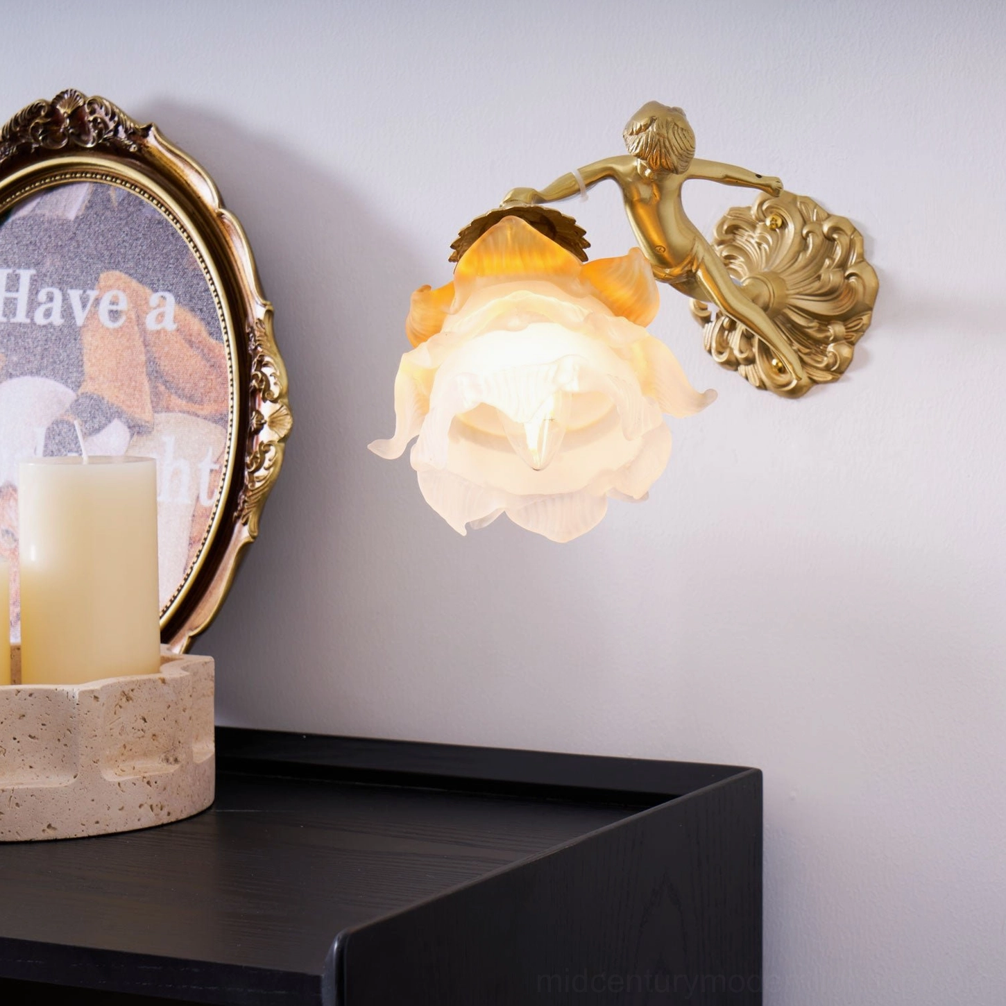 Putti cherub wall lamp mounted on classical interior wall, brass angel sculpture holding frosted flower glass shade, vintage European design aesthetic