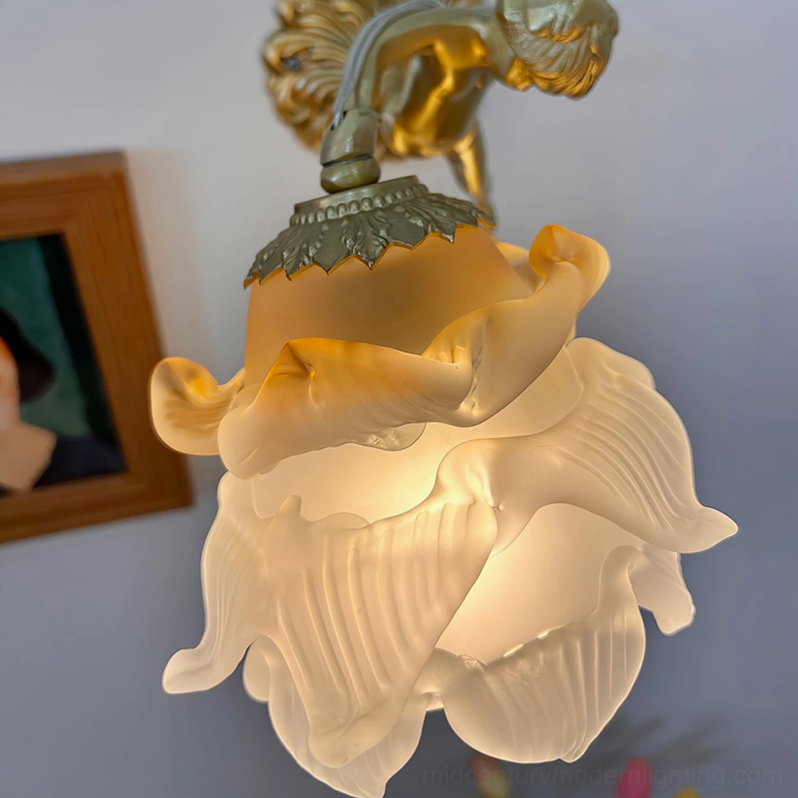 Double putti cherub wall sconce partial side view on home interior wall beside framed portrait, sculptured brass angels with vintage brass hardware