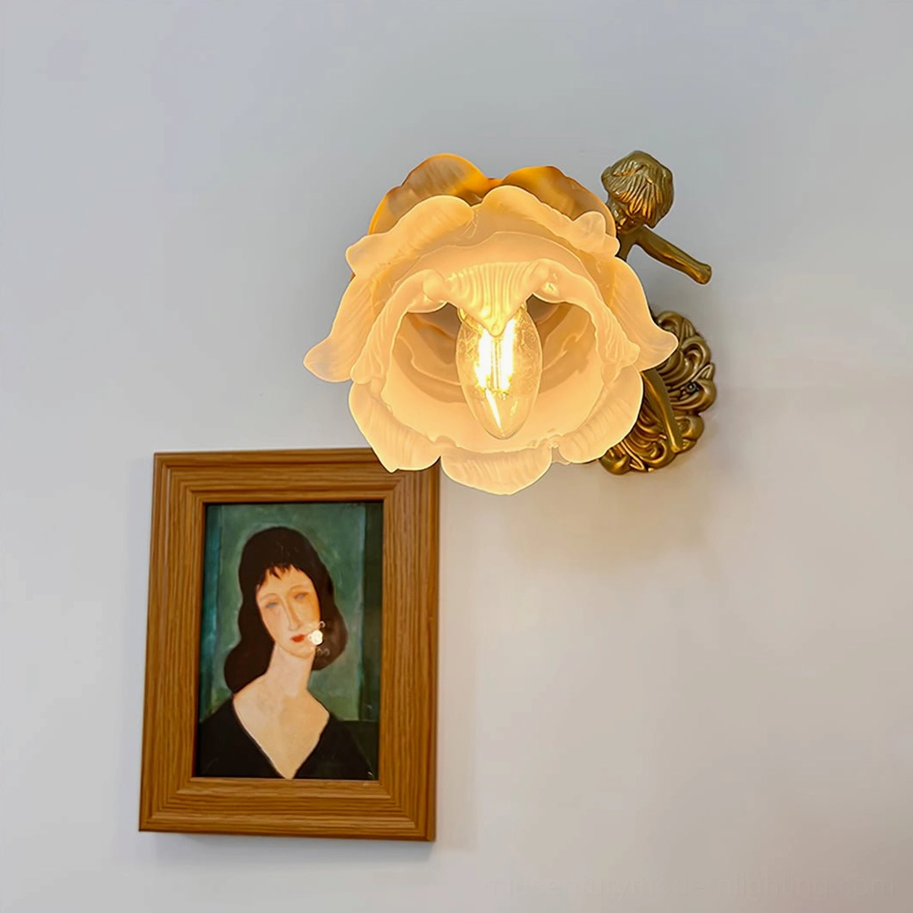 Twin putti cherub brass wall sconces mounted on bedroom wall, dual frosted glass flower shades illuminated, polished brass angel figures and shell backplates