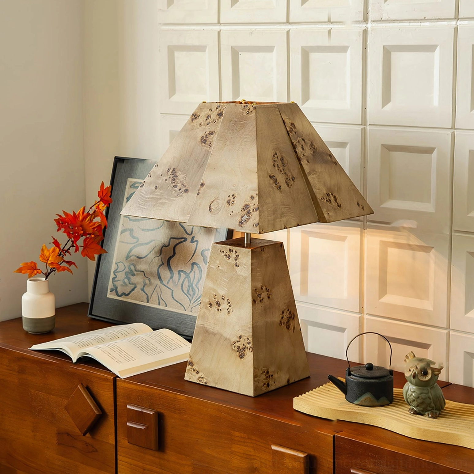 Geometric wood pyramid lamp on retro living room side cabinet with books and decorative ornaments, side angle view