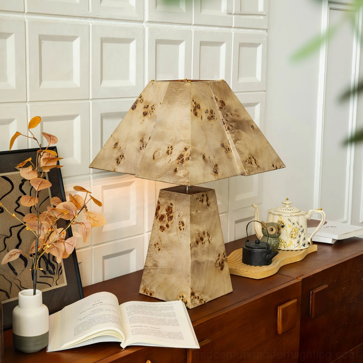 Mid-century modern pyramid wood lamp in vintage living room with potted flowers, ceramic tea set, and warm illumination