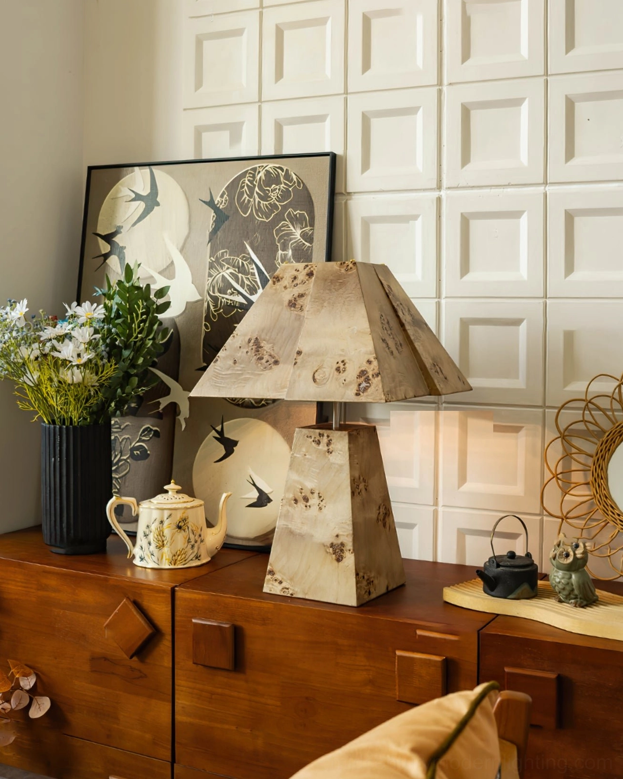 Geometric pyramid wood lamp beside window blinds with black storage cabinet and dried floral arrangement, corner lighting