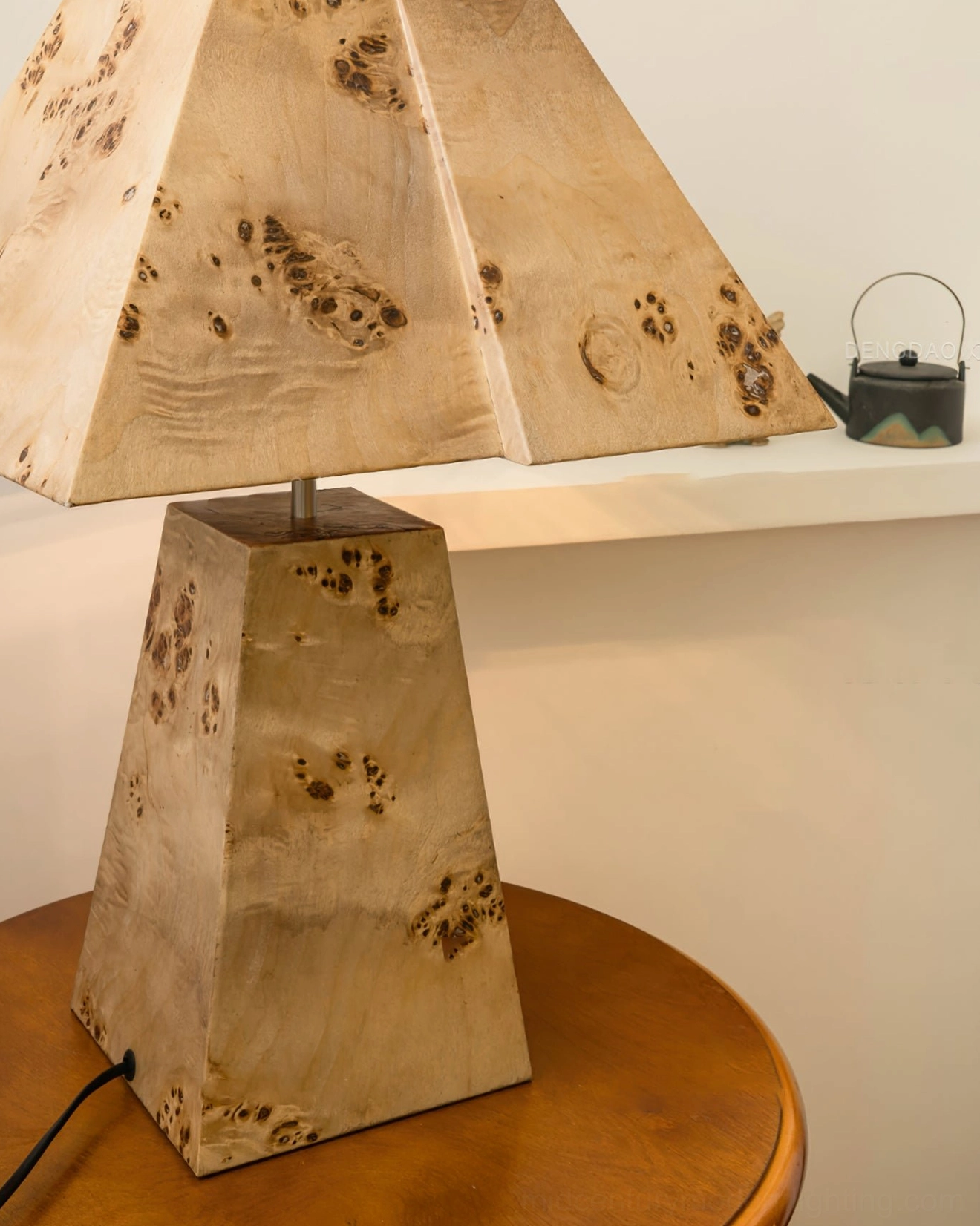 Close-up detail of pyramid wood table lamp base showing natural grain texture and geometric tapered form on wooden round table