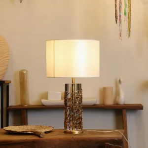 Lit quatrefoil table lamp on home shelf creating warm ambient lighting with brass crystal base details