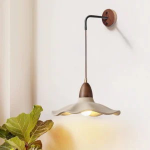 Radha modern wall lamp installed in minimalist interior corner with green foliage and neutral decor, three-quarter view