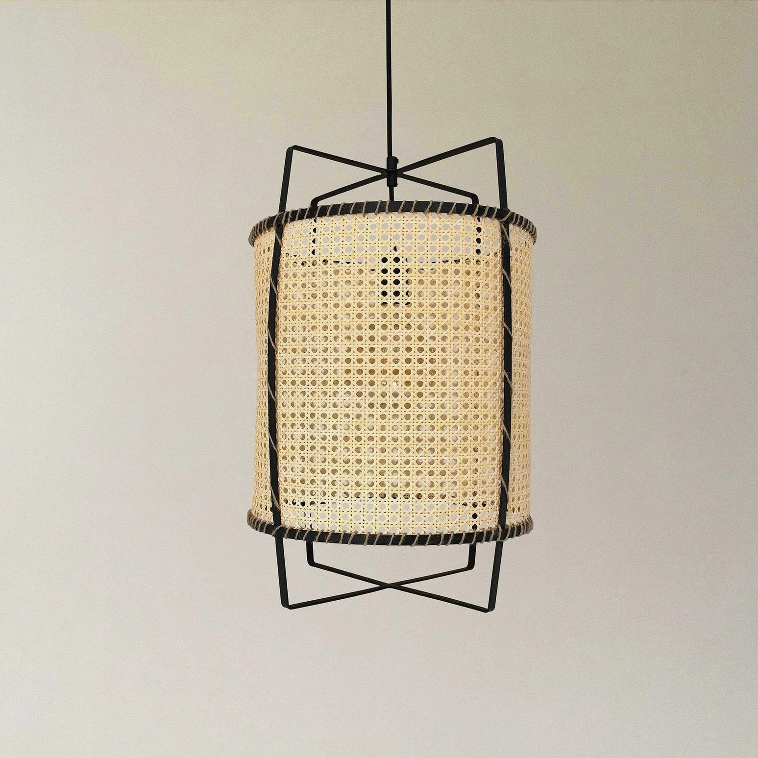 Rattan cane suspension light fixture in mid-century modern style, demonstrating open weave design and metal frame craftsmanship in interior setting