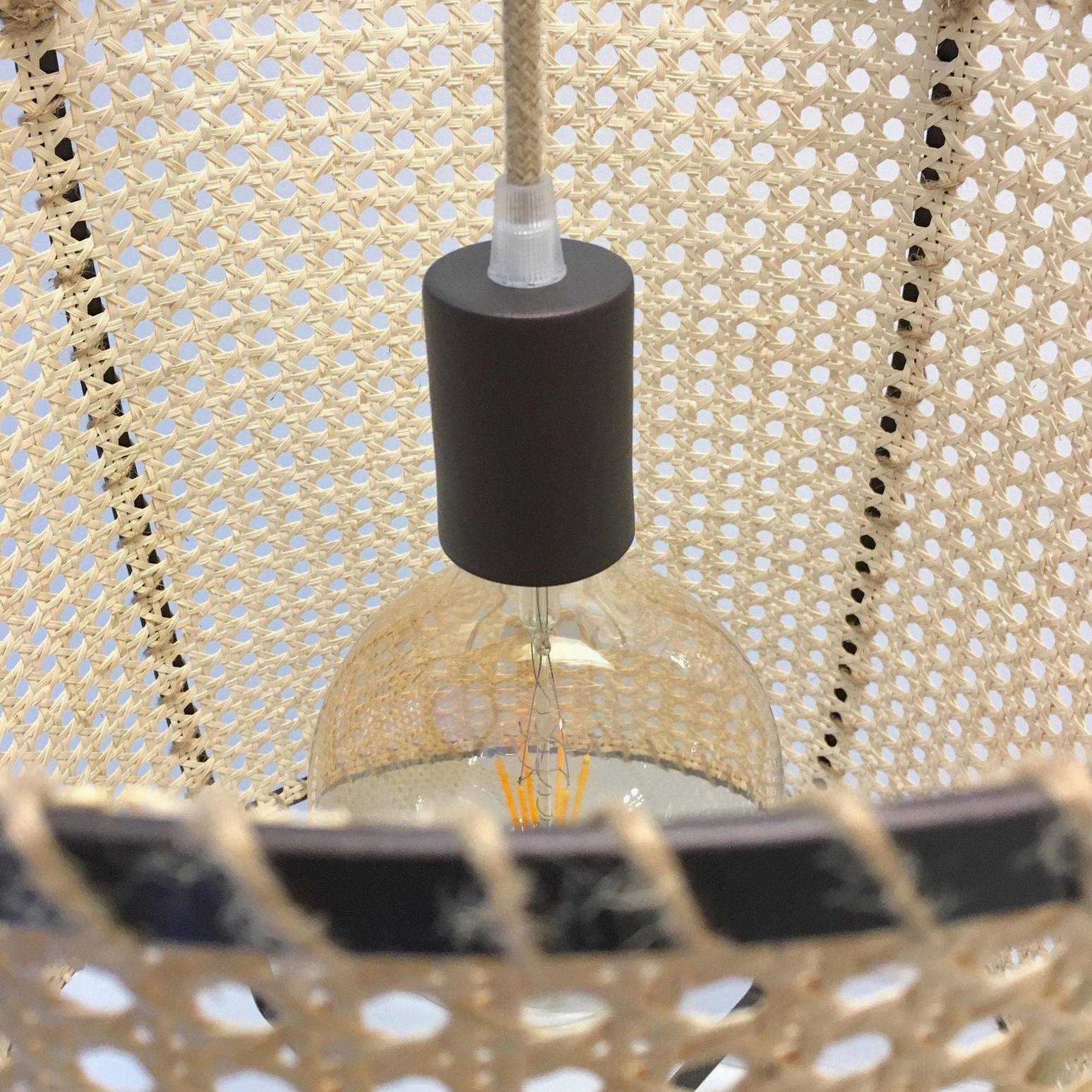 Rattan cane suspension pendant light showcasing sculptural form, warm illumination through woven mesh, and mid-century modern design principles