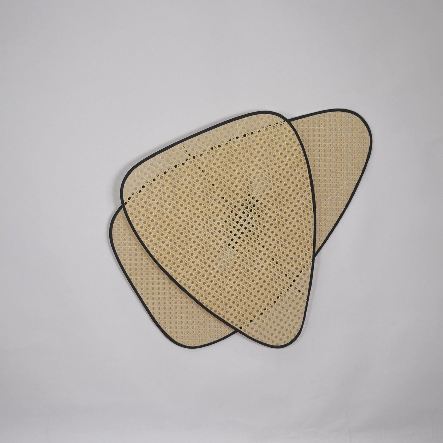 Rattan cannage wall lamp warm light creating shadow pattern on textured wall surface atmospheric effect
