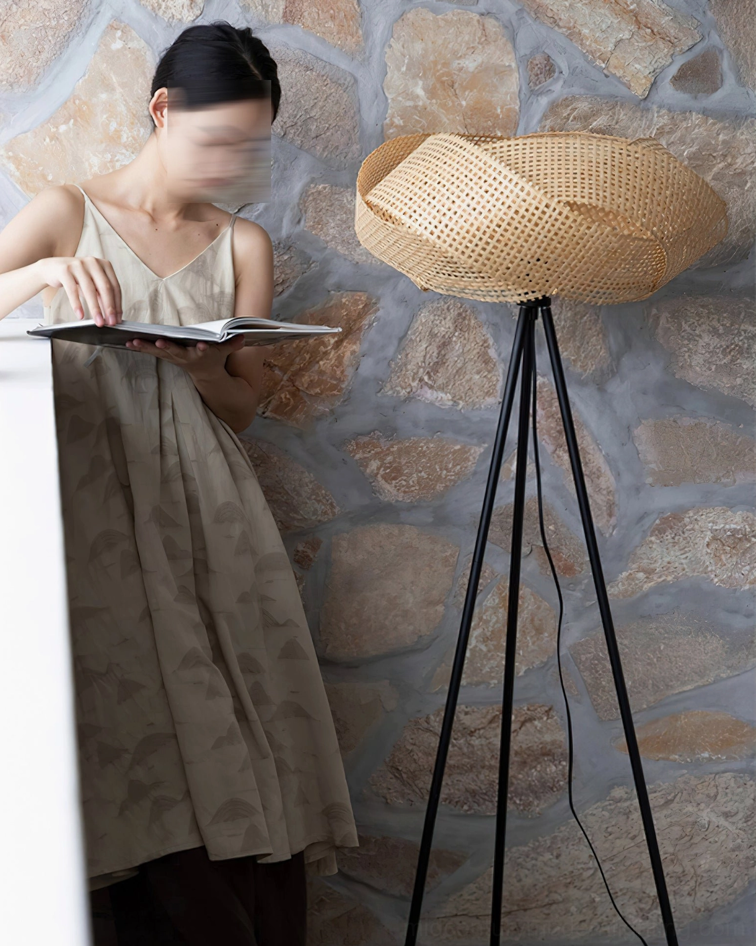 Asian woman posing beside natural rattan tripod floor lamp against stone wall, casual boho home aesthetic eye-level view