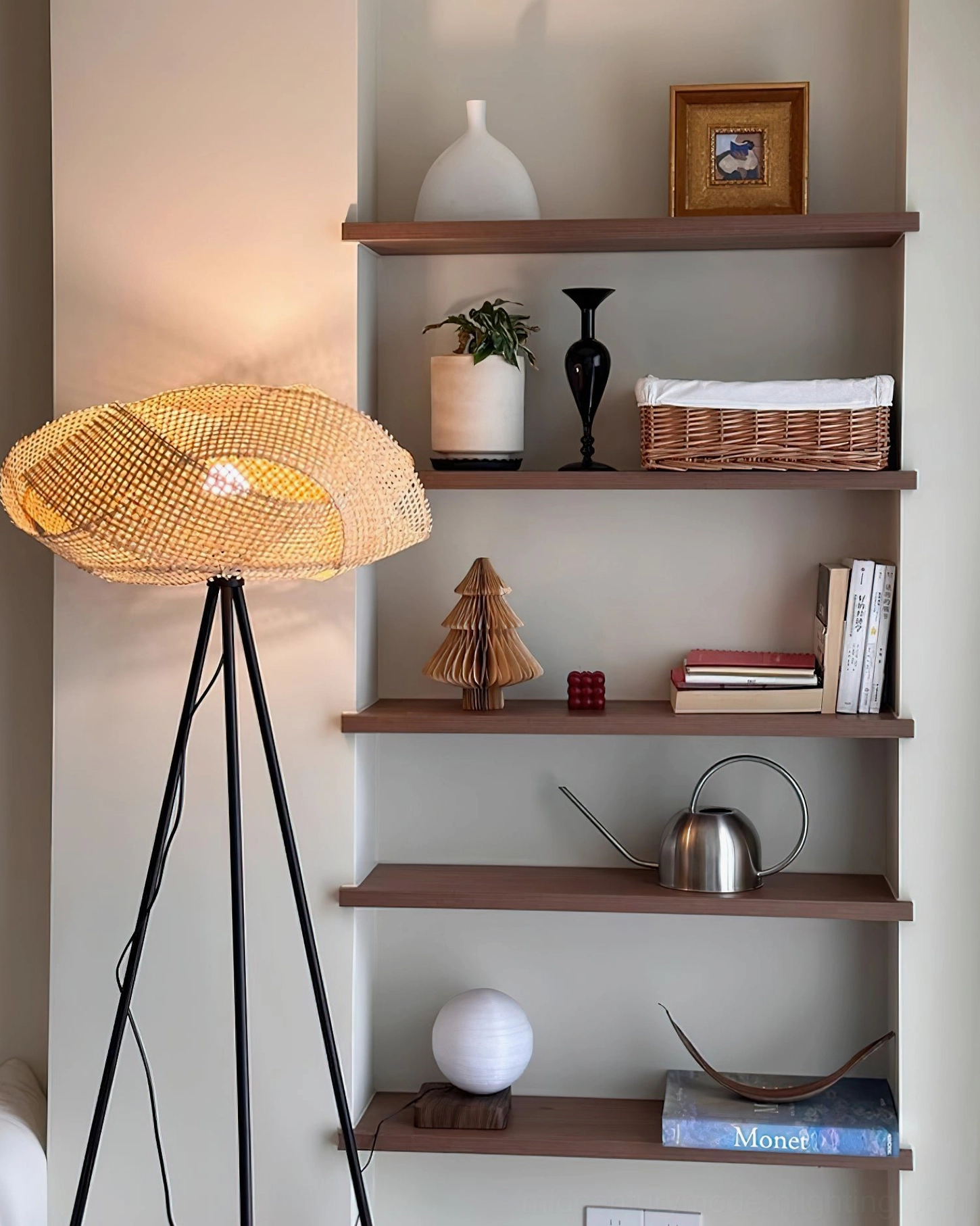 Zofia rattan floor lamp lit with warm ambient lighting, displayed on home shelf corner with three-quarter front view