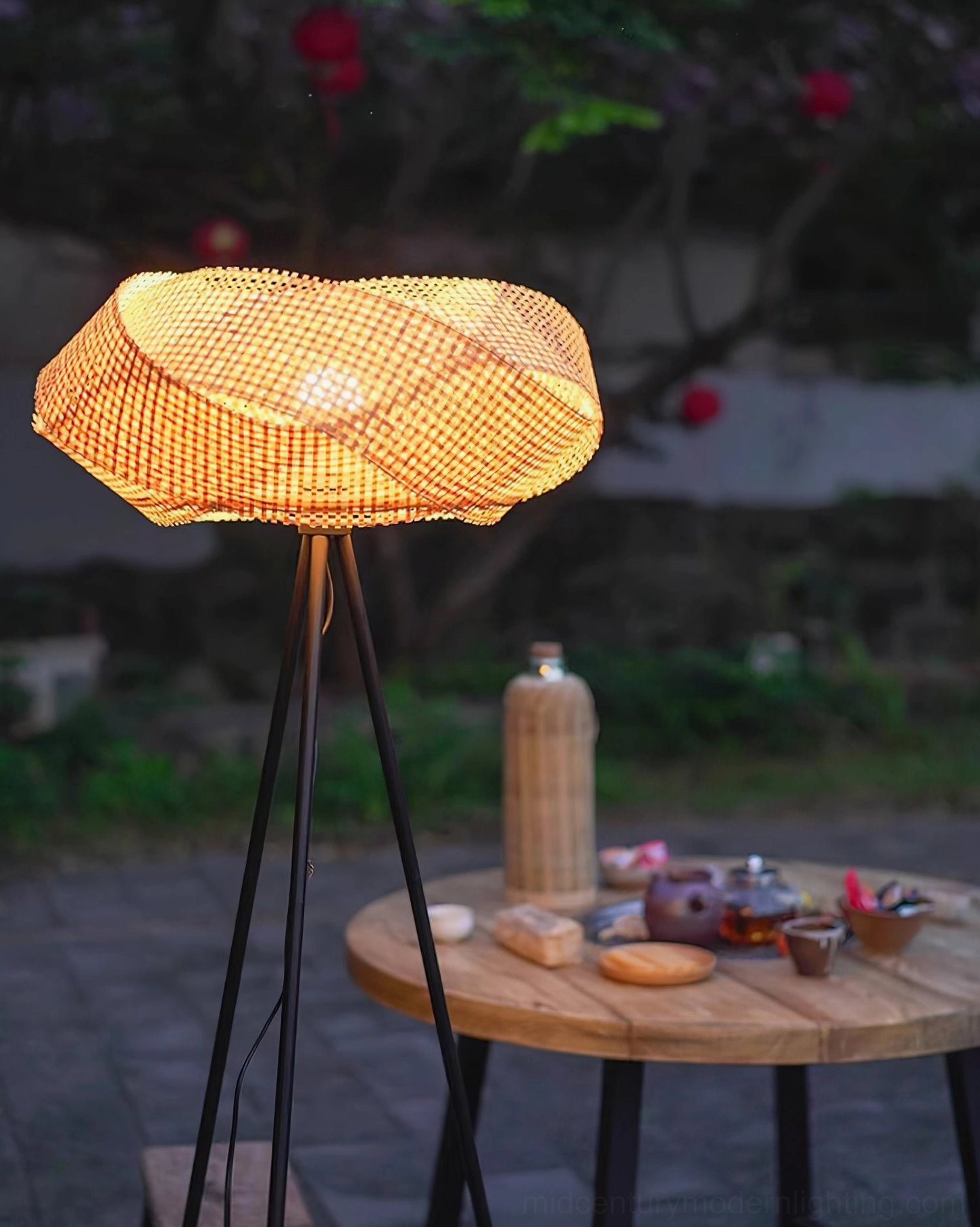 Natural rattan and matte black floor lamp with warm ambient glow in Scandinavian modern styled bedroom, cozy atmosphere