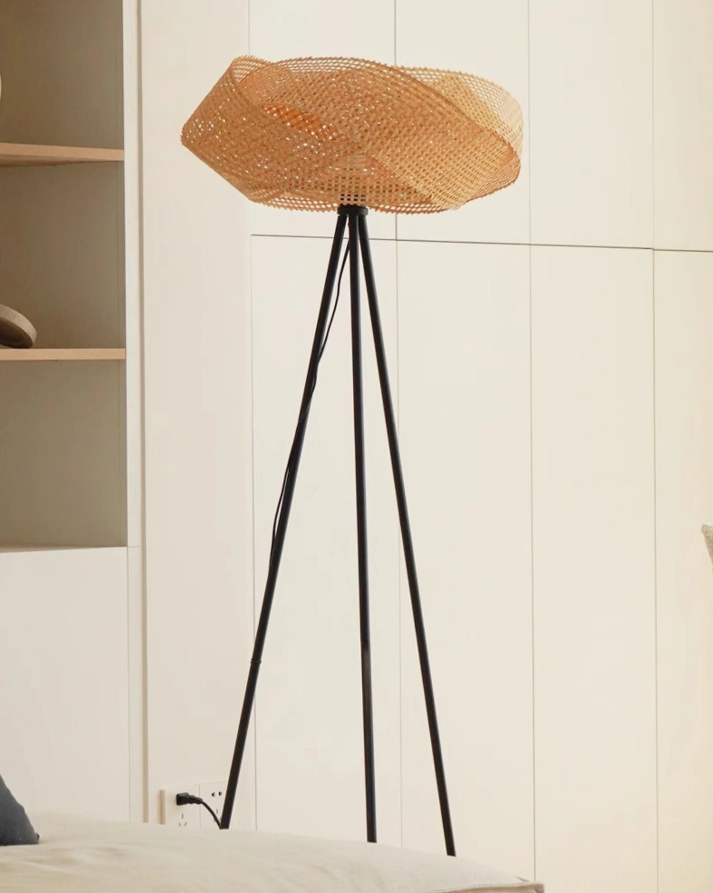 Natural woven rattan floor lamp in minimalist bedroom with built-in cabinets, open-weave lampshade design with slim metal tripod